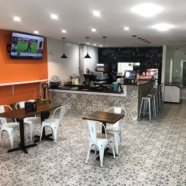 Interior of Taco Station with patterned floor tiles, orange wall, bar, and dining tables.